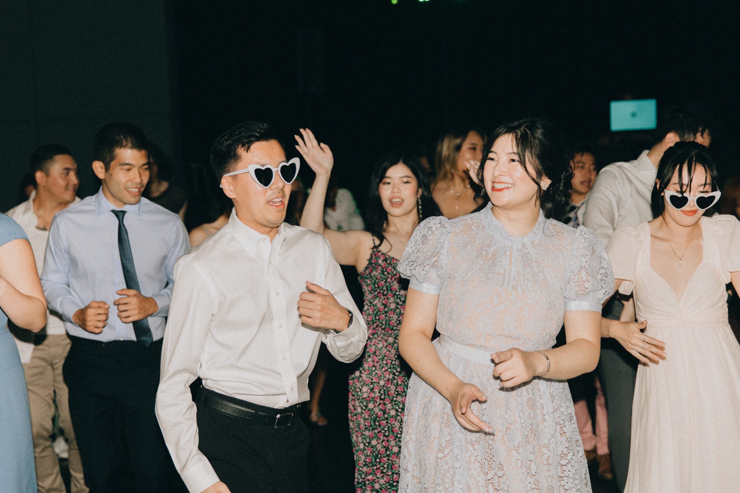 guests on the dance floor at a wedding wearing trendy heart shaped sunglasses