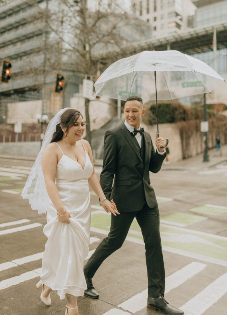 bride and groom crossing the street in rainy downtown seattle
