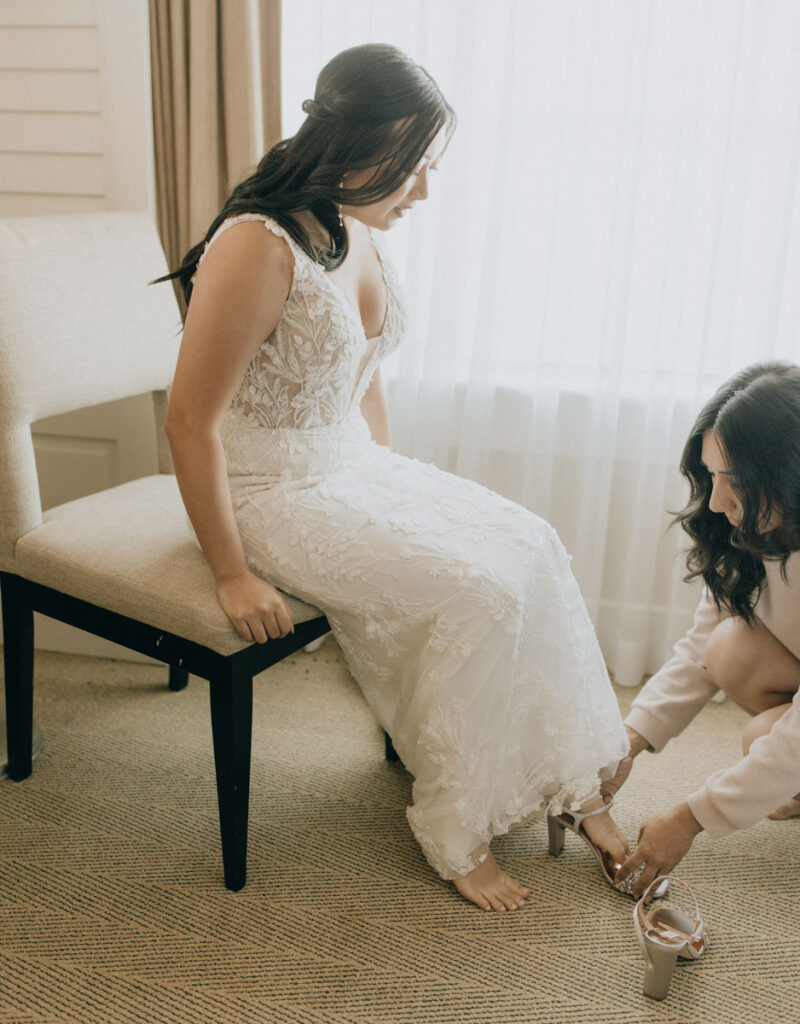 bridesmaid putting on a shoe for bride 