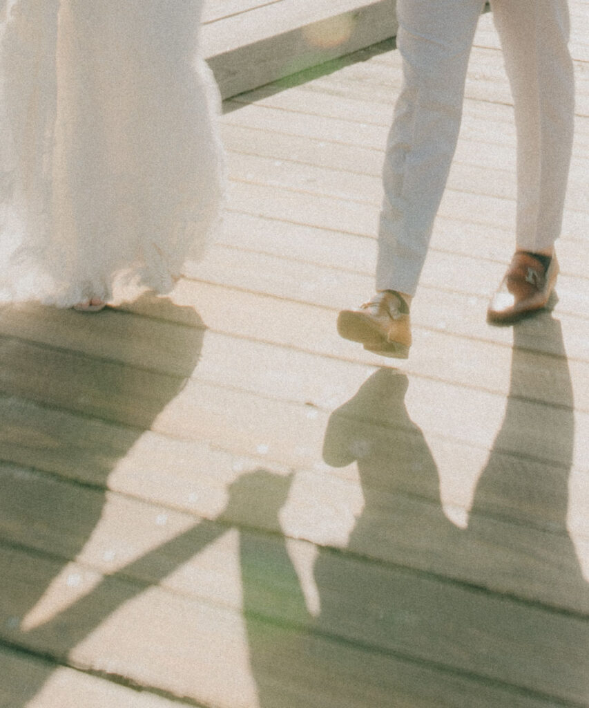 shadow of bride and groom holding hands on the dock 