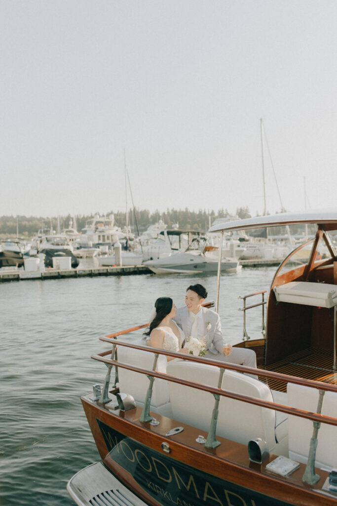 bride and groom smiling at each other while sitting on a boat
