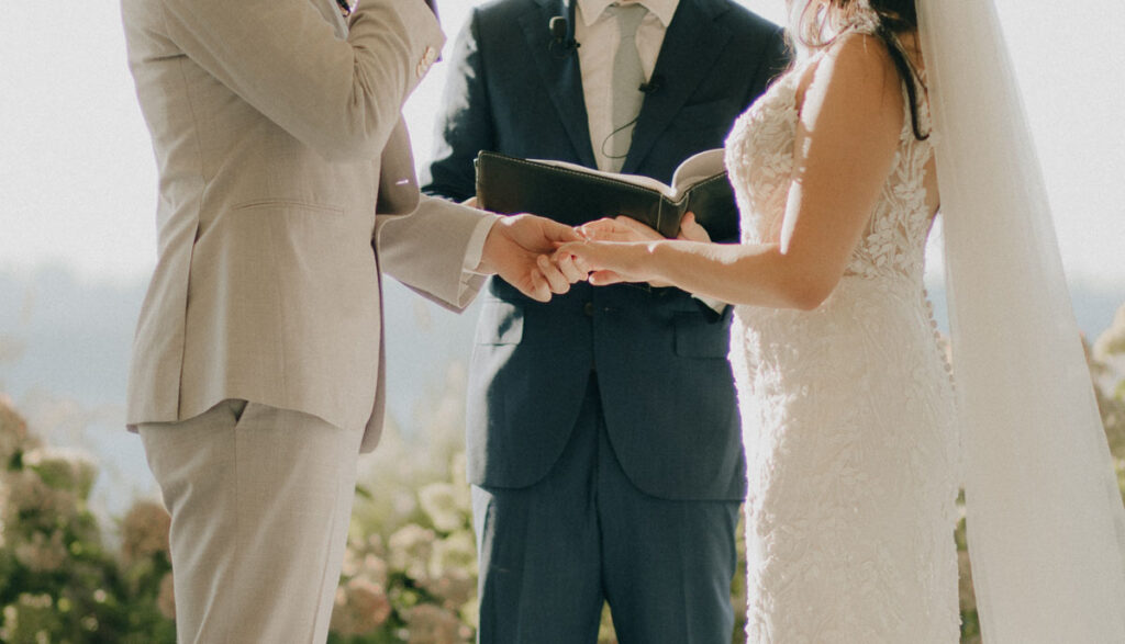 bride putting ring on groom's hands during the wedding ceremony