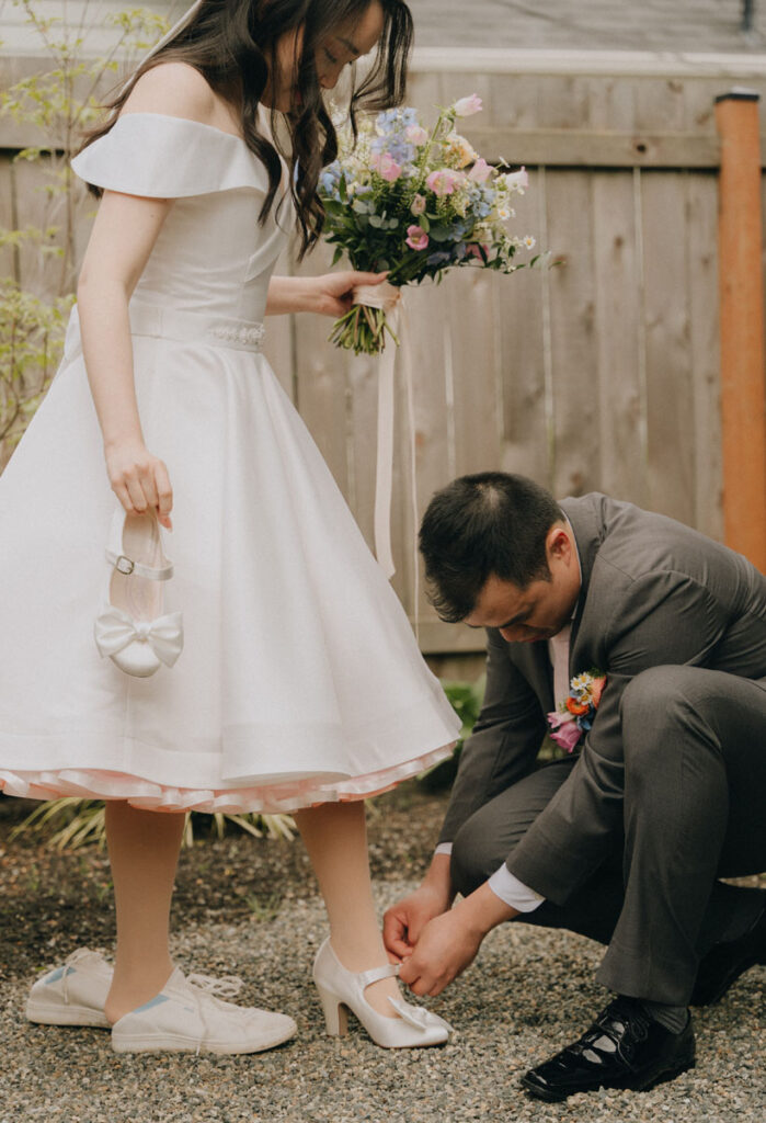 groom helping bride put her shoes on before private vows