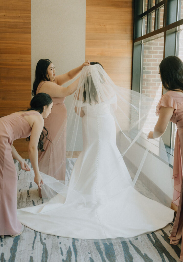 bridesmaids helping bride put on her veil