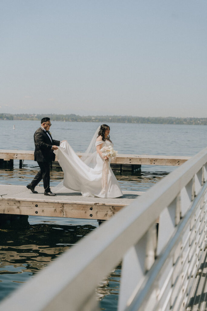 groom holding bride's dress train for her