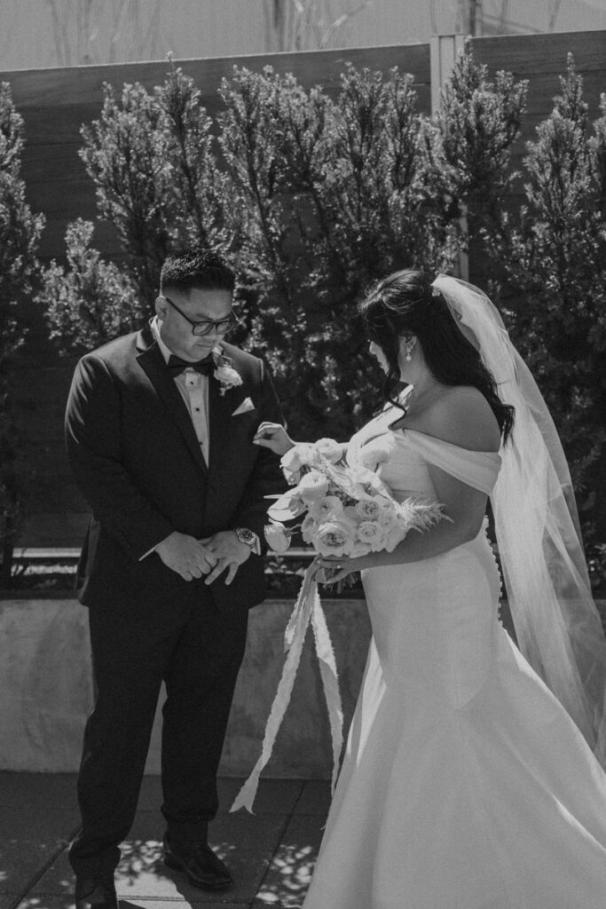 bride adjusting bowtie for groom