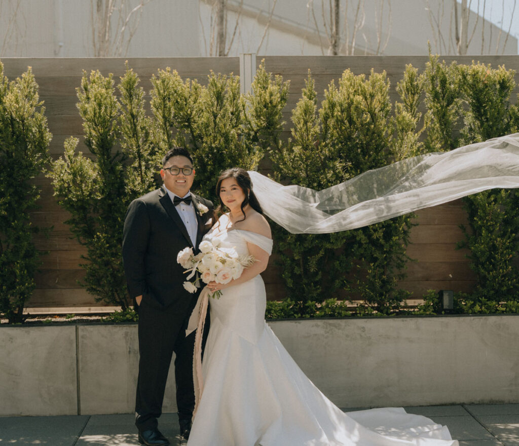 bride and groom with veil flowing in the wind