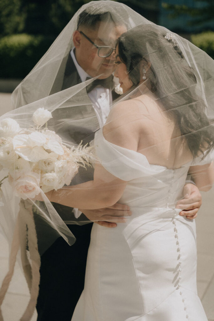 bride and groom underneath veil