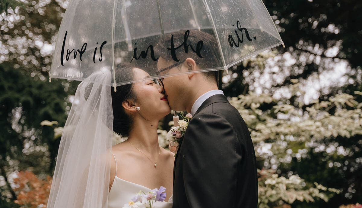 couple kissing underneath umbrella at jm cellars wedding